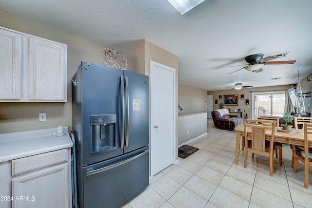 kitchen with a textured ceiling, ceiling fan, light tile patterned flooring, and stainless steel refrigerator with ice dispenser