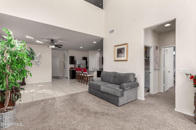 carpeted living room featuring a towering ceiling and ceiling fan