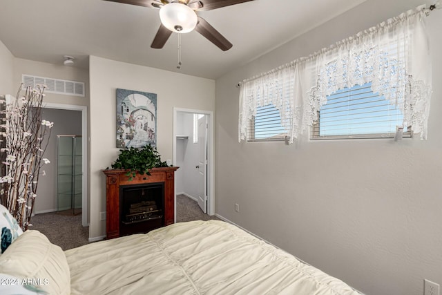 bedroom with dark colored carpet, ceiling fan, a walk in closet, and a closet