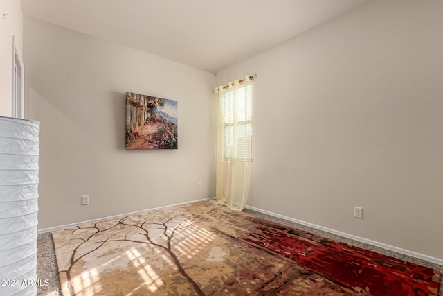 unfurnished room featuring carpet and lofted ceiling