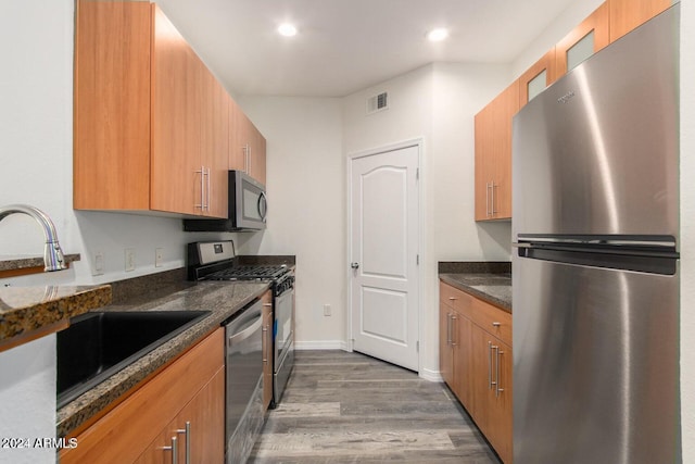 kitchen featuring dark stone counters, sink, dark wood-type flooring, and appliances with stainless steel finishes