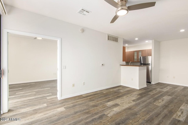 unfurnished living room featuring ceiling fan and dark hardwood / wood-style flooring