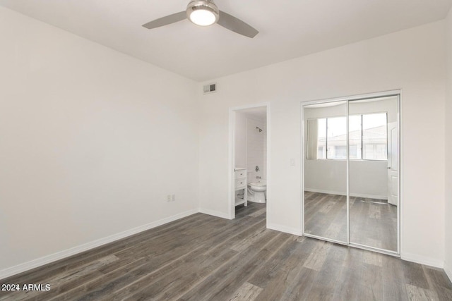 unfurnished bedroom with a closet, ensuite bath, ceiling fan, and dark wood-type flooring