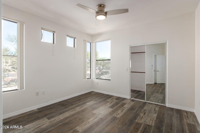 unfurnished bedroom with ceiling fan, dark wood-type flooring, and multiple windows