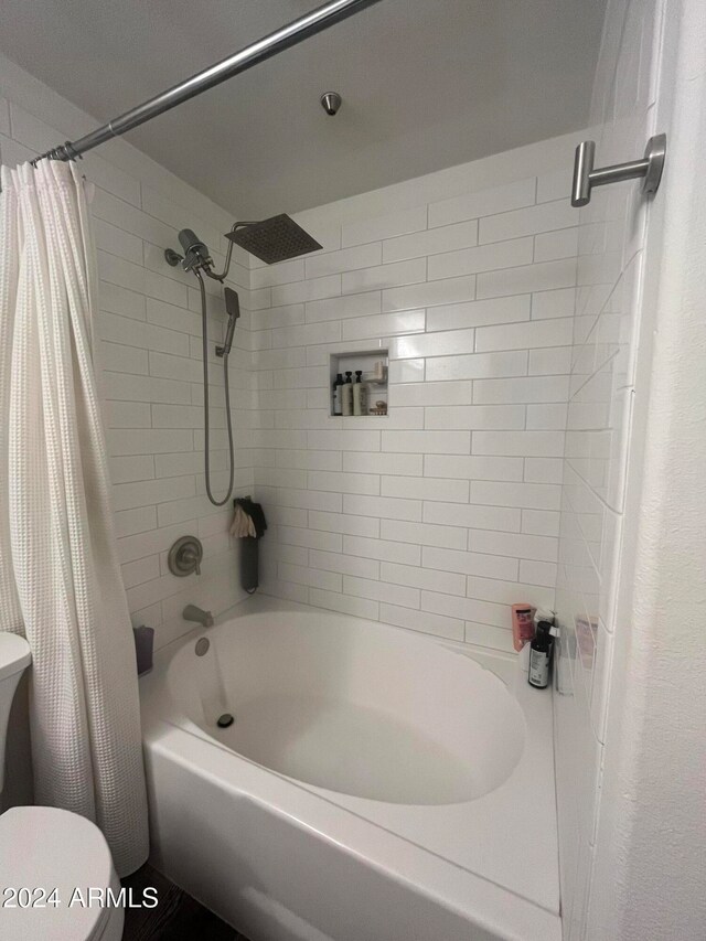 bathroom with shower / bath combination with curtain and toilet