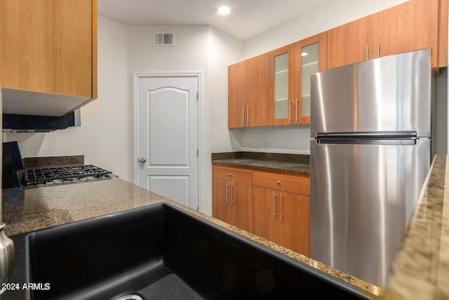 kitchen with dark stone countertops, stainless steel fridge, and stove