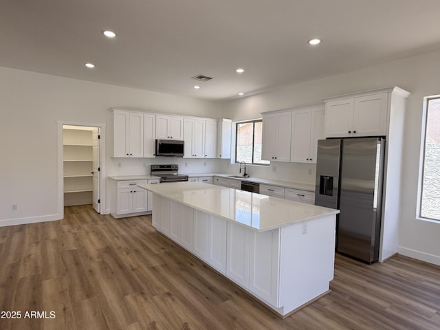 81 E Smoke Tree Rd, Gilbert, AZ 85296 - kitchen featuring stainless steel appliances, a center island, wood finished floors, white cabinets, and recessed lighting