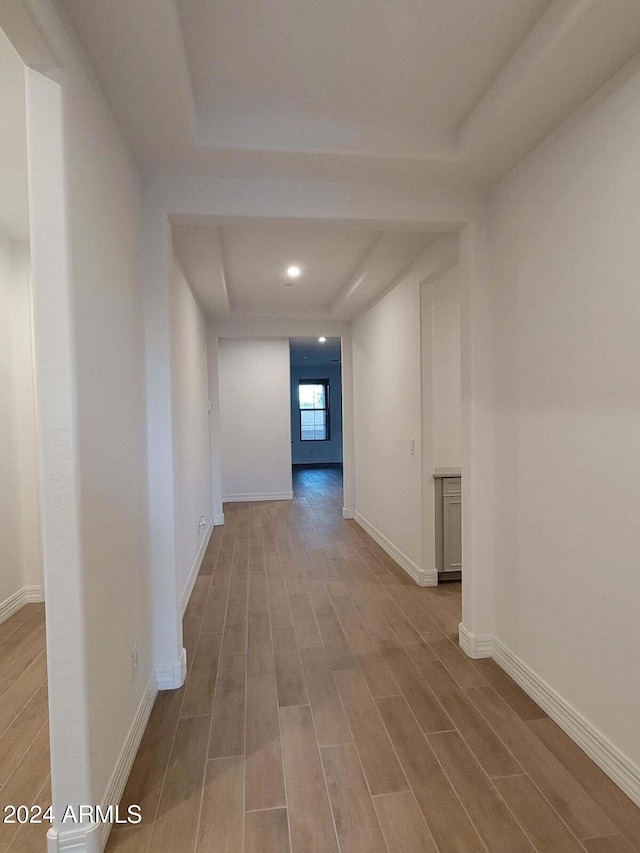 hallway featuring light hardwood / wood-style floors and a raised ceiling