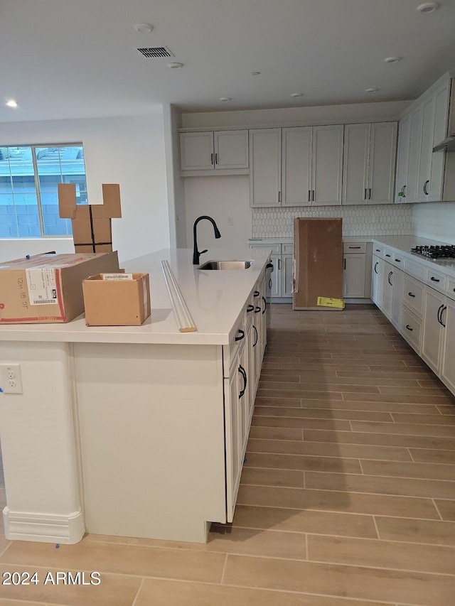 kitchen with tasteful backsplash, light hardwood / wood-style flooring, gas stovetop, and sink