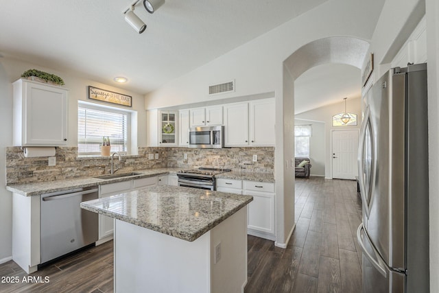 kitchen featuring white cabinets, appliances with stainless steel finishes, lofted ceiling, and sink