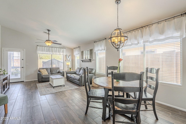 dining room featuring vaulted ceiling, dark wood-type flooring, and ceiling fan with notable chandelier