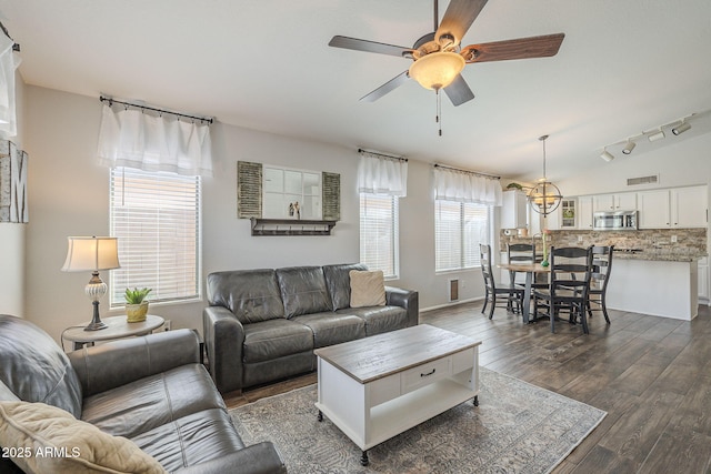 living room featuring ceiling fan with notable chandelier, dark hardwood / wood-style flooring, and rail lighting