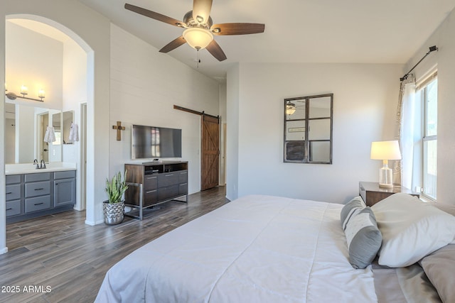 bedroom featuring connected bathroom, ceiling fan, sink, a barn door, and lofted ceiling