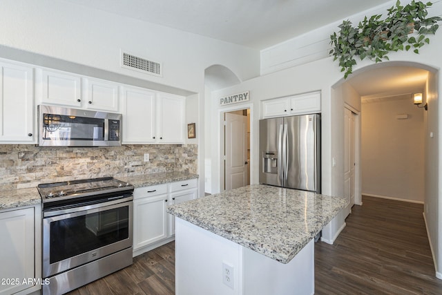 kitchen with light stone countertops, tasteful backsplash, stainless steel appliances, a center island, and white cabinetry