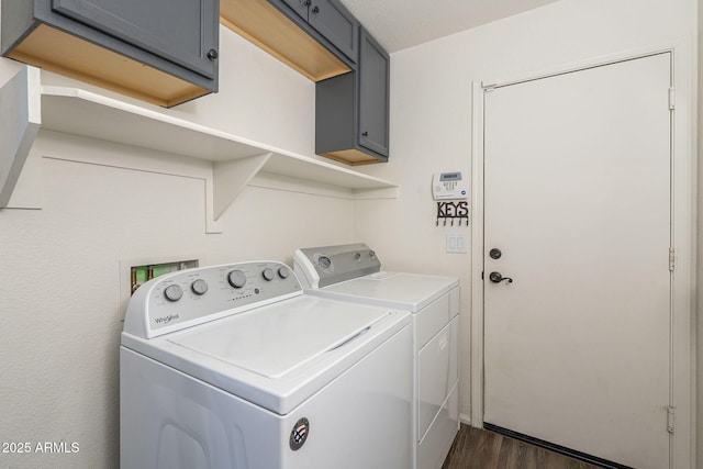 washroom featuring washer and dryer, dark wood-type flooring, and cabinets