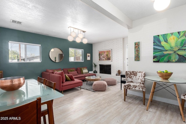 living room with a wealth of natural light, visible vents, a textured ceiling, and wood finished floors