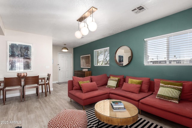 living area with visible vents, baseboards, and wood finished floors