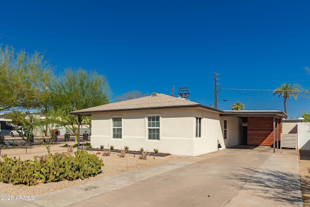 view of property exterior featuring stucco siding, an attached carport, roof with shingles, and driveway