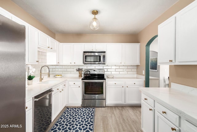 kitchen featuring tasteful backsplash, white cabinets, appliances with stainless steel finishes, and a sink