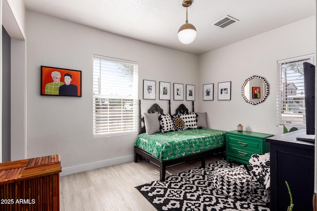 bedroom with light wood-style flooring, visible vents, and baseboards