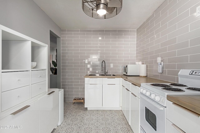 kitchen featuring white appliances, white cabinetry, tile walls, and a sink