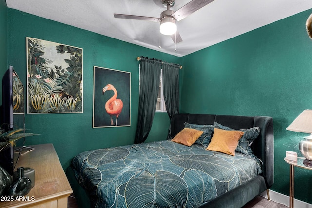 bedroom featuring a ceiling fan and a textured wall