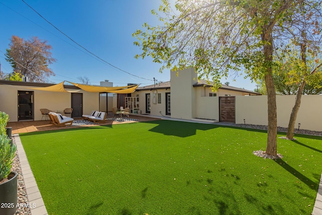 rear view of house with a patio area, a lawn, stucco siding, and fence