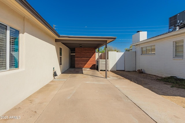 view of patio with a gate, central air condition unit, driveway, and fence