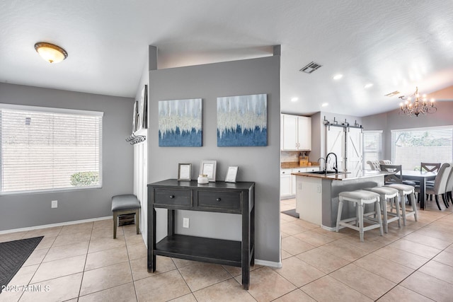 7435 W Trails Dr, Glendale, AZ 85308 - kitchen with a barn door, white cabinetry, a kitchen breakfast bar, healthy amount of natural light, and vaulted ceiling