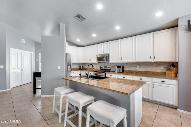 7435 W Trails Dr, Glendale, AZ 85308 - kitchen with appliances with stainless steel finishes, light tile patterned flooring, decorative backsplash, a kitchen breakfast bar, and vaulted ceiling