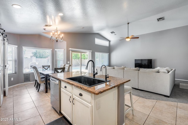7435 W Trails Dr, Glendale, AZ 85308 - kitchen featuring stainless steel dishwasher, vaulted ceiling, light tile patterned floors, light stone countertops, and a center island with sink