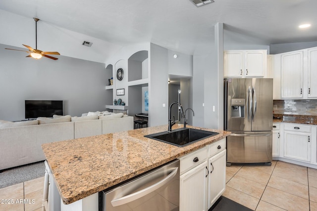 7435 W Trails Dr, Glendale, AZ 85308 - kitchen with appliances with stainless steel finishes, a ceiling fan, a center island with sink, backsplash, and light tile patterned floors
