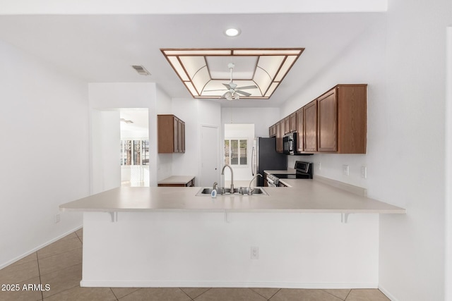 kitchen with stainless steel appliances, a raised ceiling, sink, and kitchen peninsula