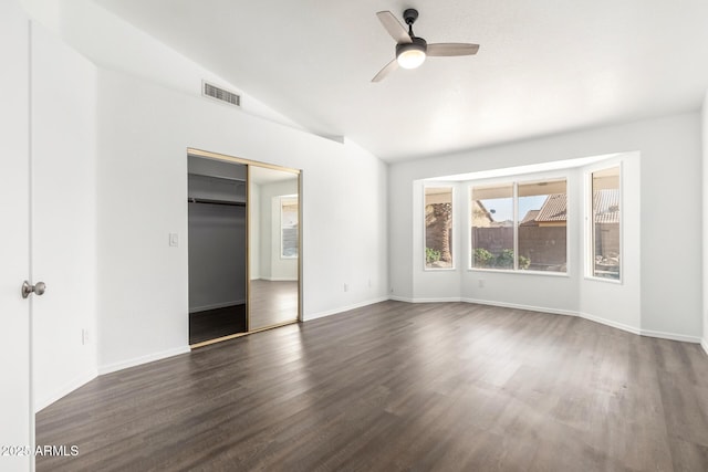 unfurnished bedroom featuring vaulted ceiling, dark wood-type flooring, ceiling fan, and a closet