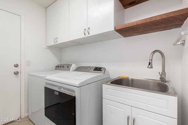 clothes washing area with sink, light tile patterned floors, cabinets, and washer and dryer