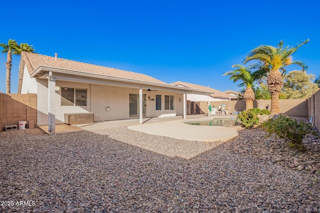 back of property with a fenced in pool and a patio area