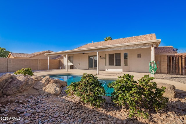 back of property with a fenced in pool and a patio