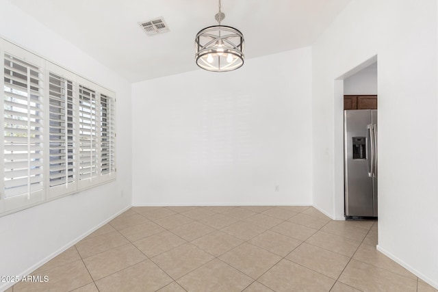 spare room with light tile patterned flooring and a notable chandelier