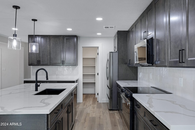 kitchen with stainless steel appliances, light stone counters, light hardwood / wood-style floors, and sink