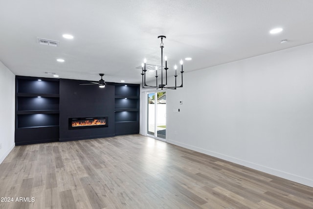 interior space featuring ceiling fan with notable chandelier and light hardwood / wood-style flooring