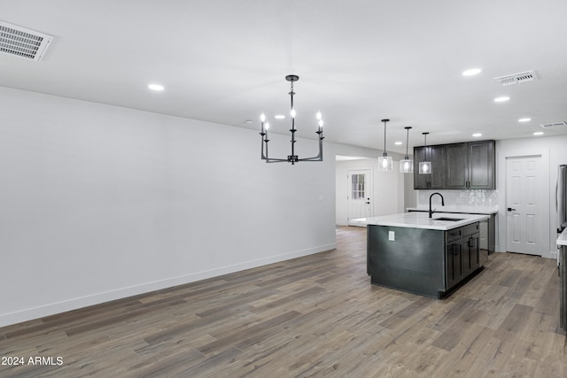 kitchen with pendant lighting, dark hardwood / wood-style flooring, sink, and a kitchen island with sink