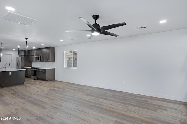 living room featuring ceiling fan with notable chandelier, sink, and light hardwood / wood-style flooring