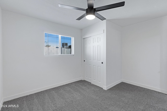 empty room featuring ceiling fan and dark carpet