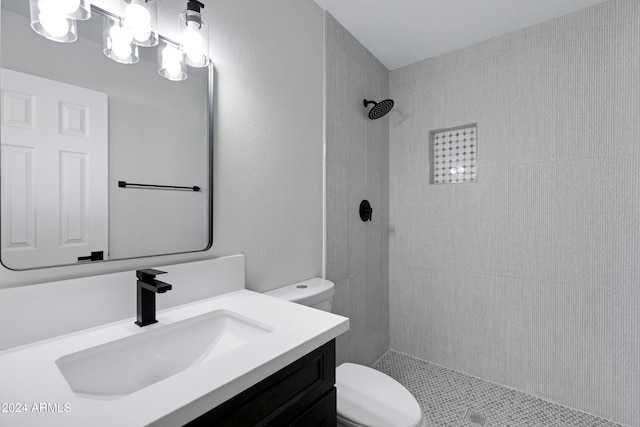 bathroom with a tile shower, vanity, and toilet