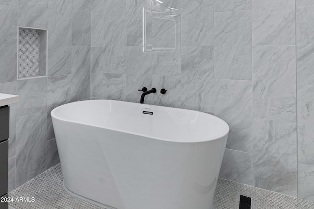 bathroom featuring tile patterned floors, vanity, tile walls, and a tub