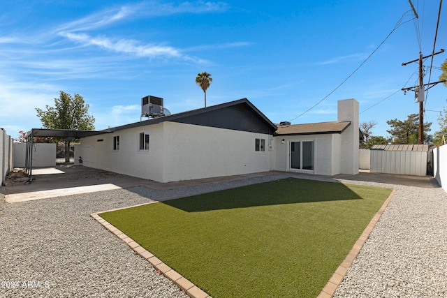 back of house with central AC, a yard, and a carport