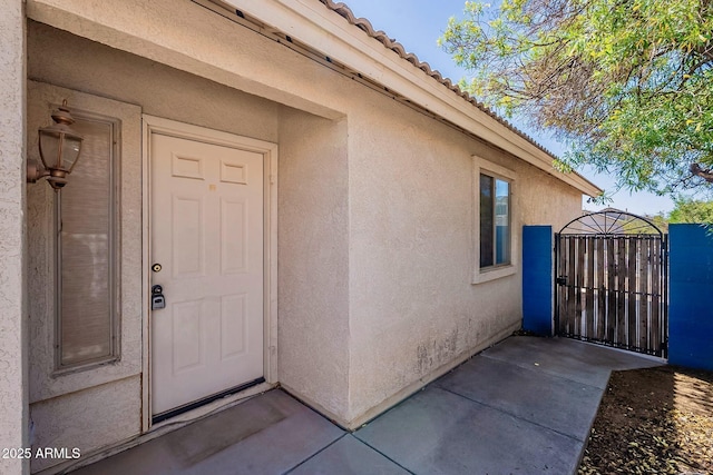 8660 E Nido Ave, Mesa, AZ 85209 - view of exterior entry with stucco siding, a gate, and a tile roof