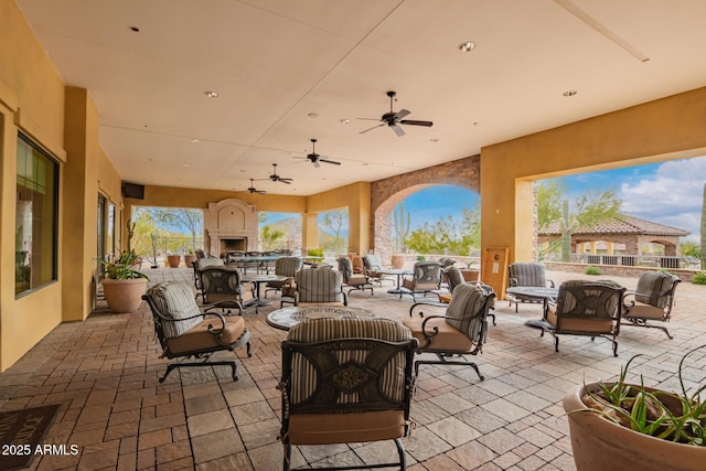 view of patio with an outdoor living space with a fireplace and ceiling fan