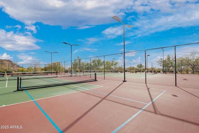 view of tennis court with community basketball court and fence