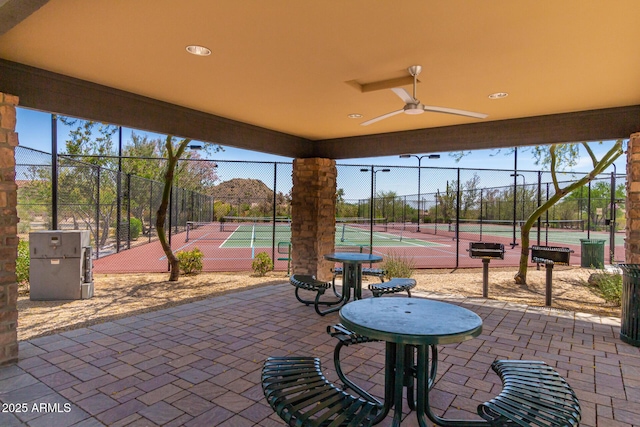 view of patio with ceiling fan, a tennis court, and fence